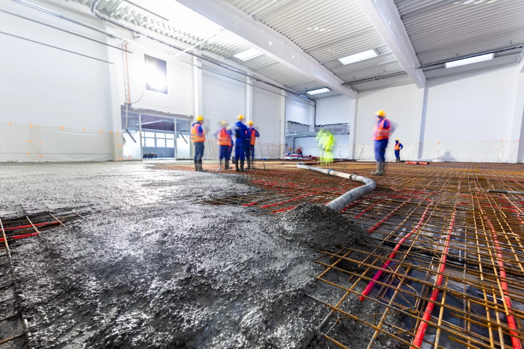 workers pour concrete on floor with heating