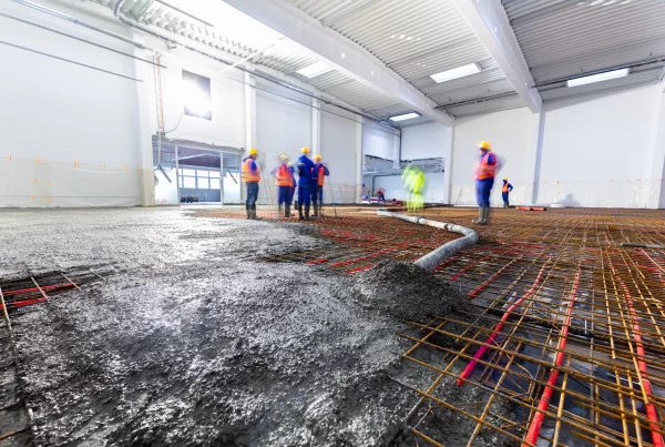 workers pour concrete on floor with heating
